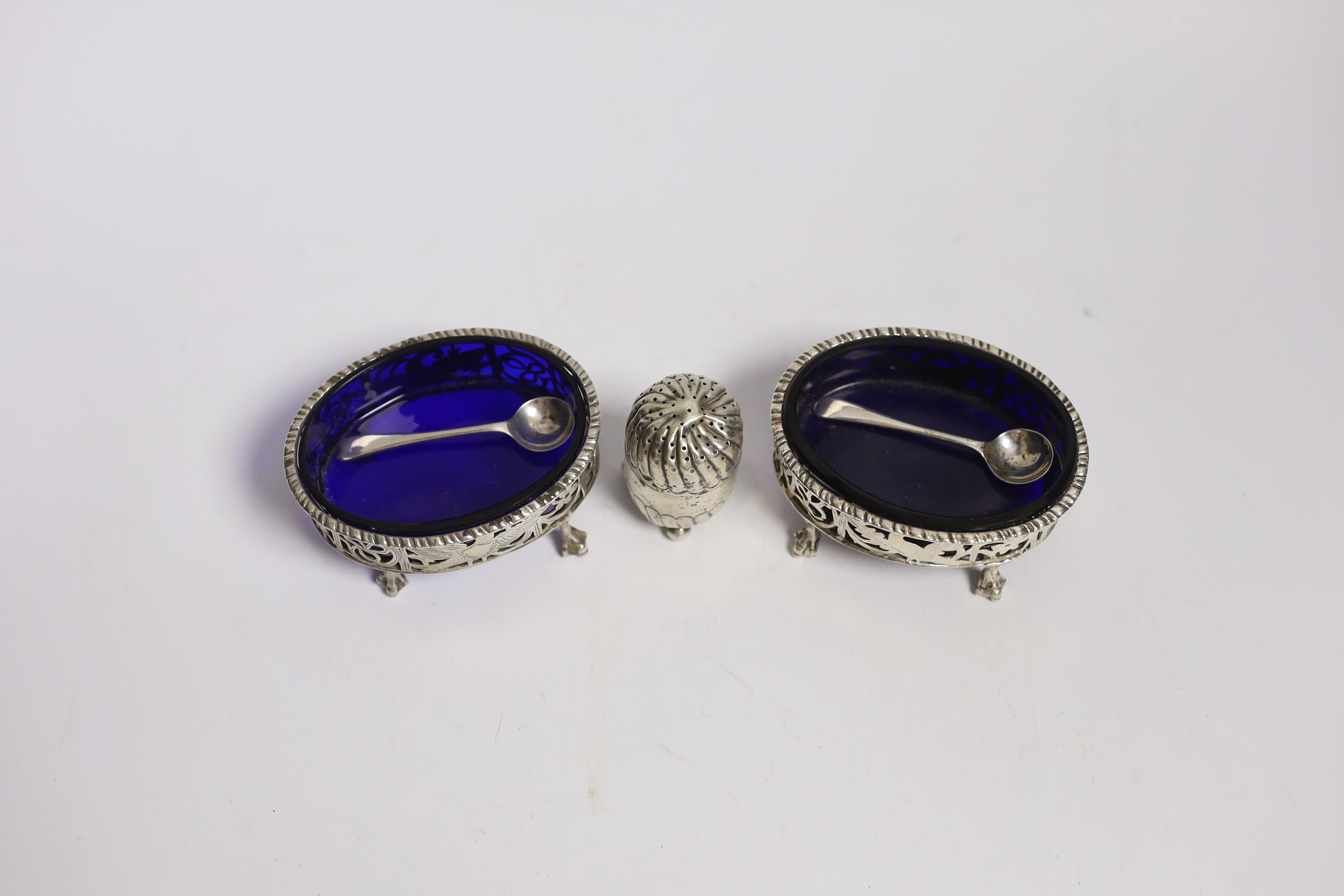 A pair of Edwardian pierced silver oval salts, Charles Stuart Harris, London, 1901/2, 82mm(a.f.), with blue glass liner and later associated spoons, together with a silver pepperette.